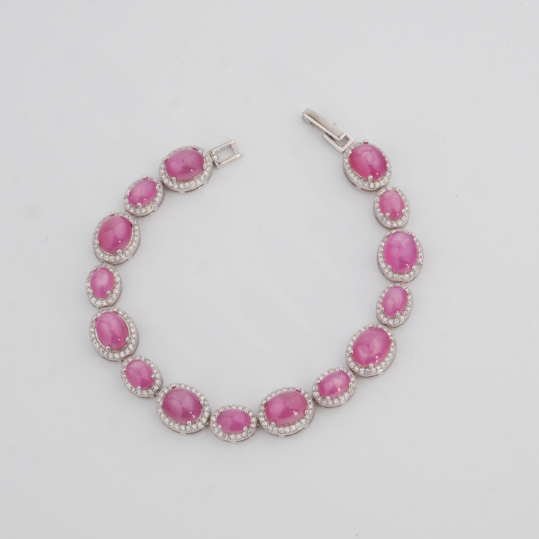 Pulsera elegante de plata de ley 925 para mujer con rubíes rojo-rosado tallados en cabujón y rodeados por marcos ovales de circonitas, exhibida en 1.jpg.