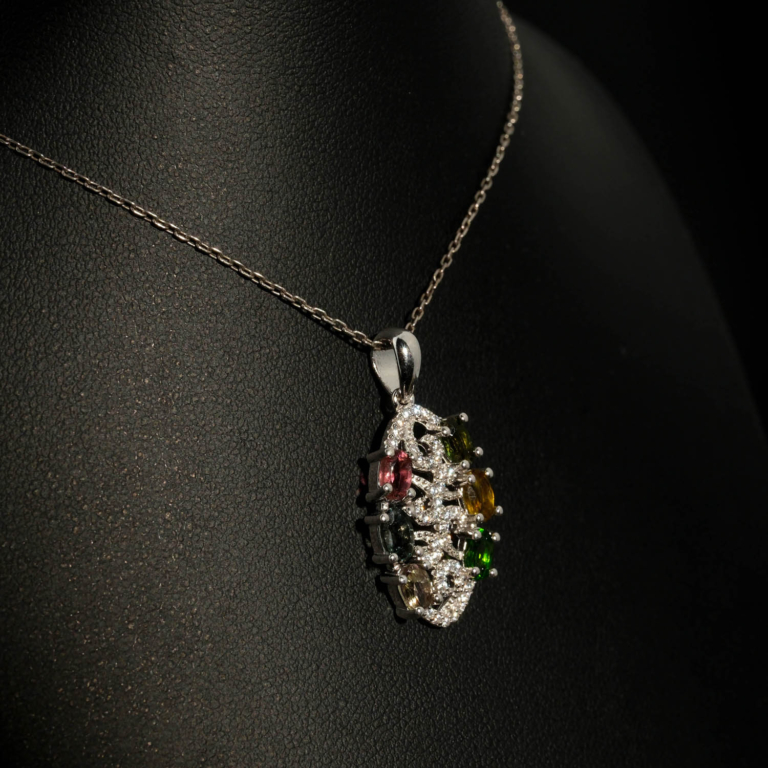 A luxury designer necklace featuring original faceted oval multicolor tourmaline gemstones arranged in a sterling silver filigree pendant with zircon accents.