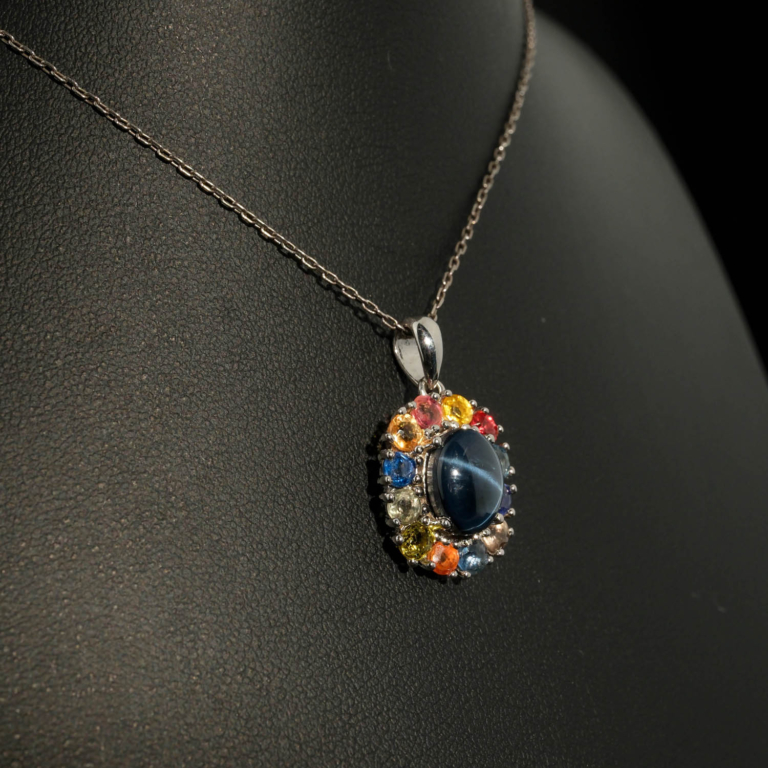 Luxus-Design-Kette aus 925er Sterlingsilber mit einem ovalen Cabochon-Sternsaphir, umgeben von einem Halo aus bunten facettierten Saphiren.