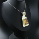 Collar de colección hecho a mano en plata de ley 925 con una piedra de ámbar natural original en forma de trapecio, decorado con esmalte verde pistacho y elegantes motivos de plata.