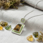Handgefertigte Sammler-Halskette aus 925er Sterlingsilber mit einem trapezförmigen originalen Naturbernstein, verziert mit pistaziengrüner Emaillearbeit und eleganten Silbermotiven.