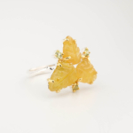 A luxury women's statement ring featuring an original carved leaf yellow sapphire with faceted green peridot gemstones set in a 925 sterling silver design.