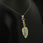 A luxury designer necklace featuring a hand-carved leaf prehnite and faceted peridot gemstones set in 925 sterling silver.