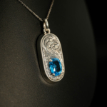 925 sterling silver necklace featuring an oval facet cut original blue topaz natural stone and masterfully engraved surroundings.