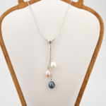 Colgante de diseño de lujo en acero inoxidable con tres perlas naturales de océano tricolores en forma de gota.