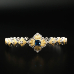 Brazalete de diseño de lujo en plata de ley 925 de estilo barroco con baño de oro y una piedra azul central.