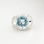 A luxury women's statement ring featuring an original 4.5ct oval faceted blue topaz gemstone set in a high-prong 925 sterling silver artisan design.