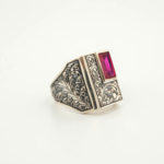 Anello da uomo in argento 925 con una pietra naturale di rubino originale con taglio a faccette rettangolare in una cornice rettangolare con motivi floreali fatti a mano.