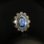 Anillo de hombre de plata 925 con una piedra natural de zafiro estrella original de talla cabujón ovalada y un entorno magistralmente grabado.