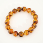 A stylish gemstone statement bracelet featuring original 12-13mm Baltic amber round beads on a stretch band for adults.