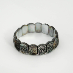 Bracelet de luxe en nacre naturelle foncée sculptée de motifs roses avec maillons style Rolex.