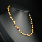 A certified natural multi-color Baltic amber baby teething necklace featuring individually knotted beads and a safety screw clasp.