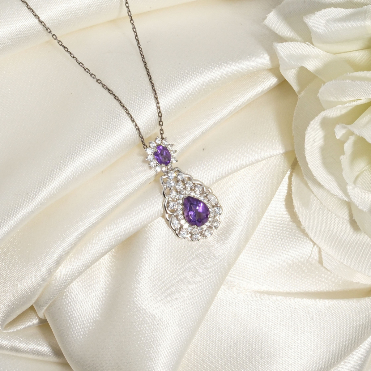 Collana da donna in argento 925 con pendente a goccia in ametista naturale viola su tessuto bianco.