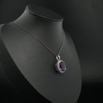 Pendentif halo pour femme en améthyste violette naturelle ovale et argent sterling 925 sur tissu blanc.