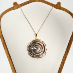 Pendentif sculpté en forme de rose en nacre naturelle grise avec chaîne en acier inoxydable doré.
