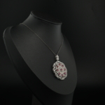 Pendentif médaillon pour femme en rubis rouge naturel et argent 925 orné de micro zircons sur tissu blanc.