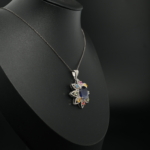 Pendentif fleur pour femme en saphir bleu foncé, saphirs multicolores et diamants naturels en argent 925 sur tissu blanc.