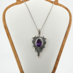 Pendentif bouclier unisexe en améthyste violette naturelle et argent 925 gravé oxydé sur tissu blanc.