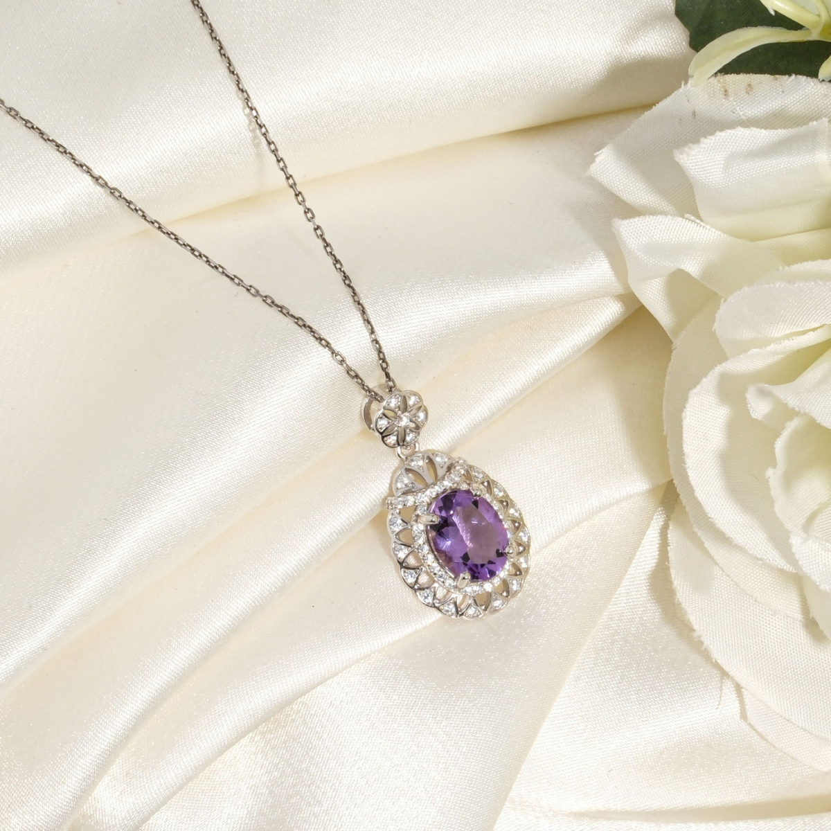 Damen Halskette aus 925 Silber mit natürlichem ovalem Amethyst und floralem Anhänger auf weißer Seide.