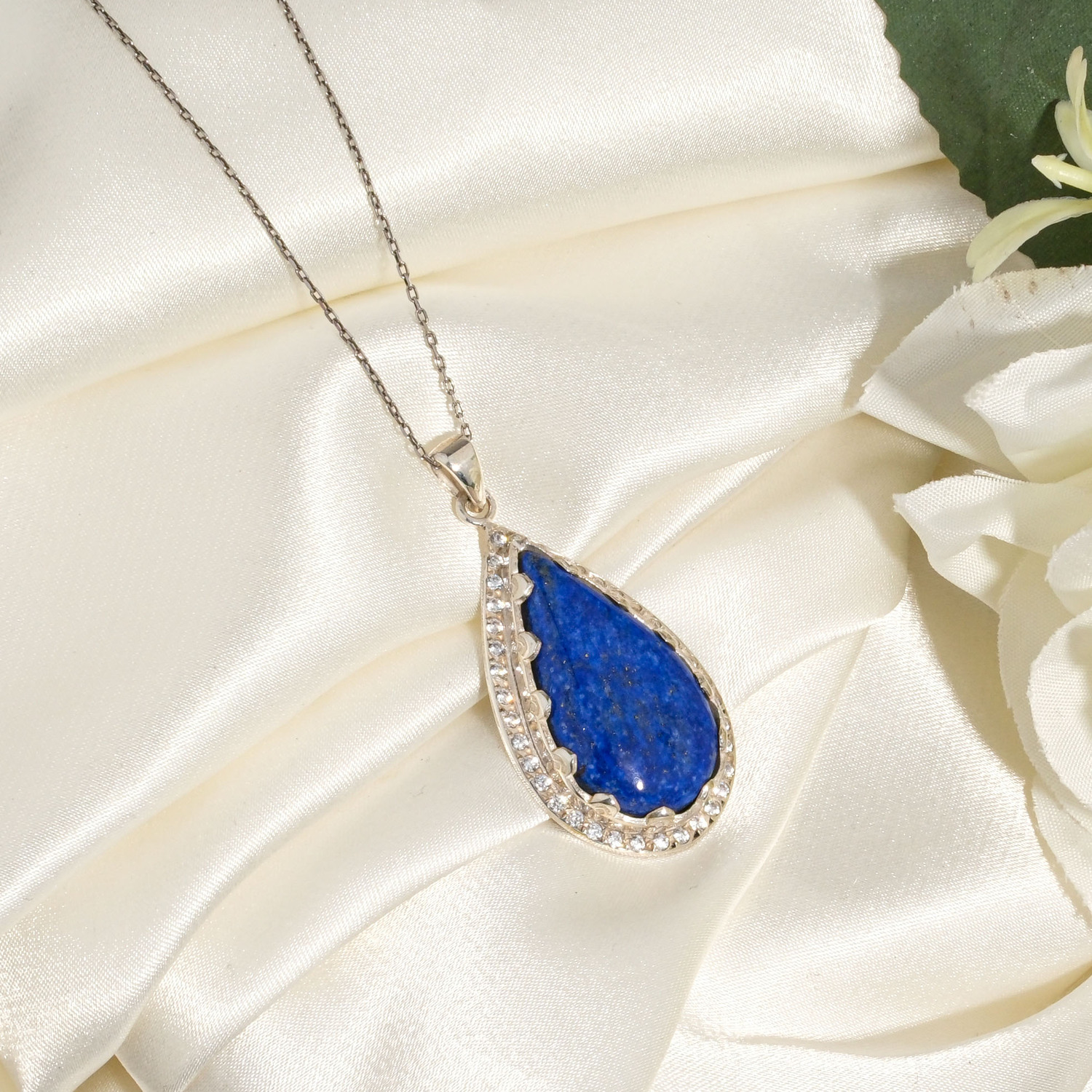 halskaede-lapis-lazuli-aedelsten-emalje-925-solv-dame-drabe Elegant 925 sølv halskæde til kvinder med dråbeformet naturlig mørkeblå lapis lazuli ædelsten og emaljedetaljer.