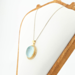 Damen Halskette aus vergoldetem 925 Silber mit ovalem Aquamarin-Cabochon und funkelndem Zirkonia-Kranz.
