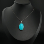 Natural oval Arizona turquoise gemstone pendant necklace in 925 sterling silver on white silk.