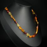 A women's necklace featuring natural smooth multi-colored Baltic amber beads with a stainless steel lobster clasp and 7cm extender chain.