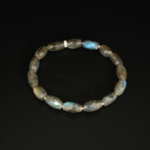 A 925 sterling silver detailed stretch bracelet featuring 8x11.5mm natural faceted barrel-cut iridescent labradorite gemstones.