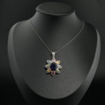 Natural multicolor sapphire and diamond flower design pendant necklace in 925 sterling silver on white silk.