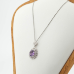 Faceted oval natural purple amethyst gemstone halo pendant with flower detail in 925 sterling silver on white silk.