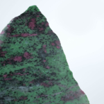 An authentic 928g natural ruby in zoisite anyolite raw polished display slab on an acrylic stand.