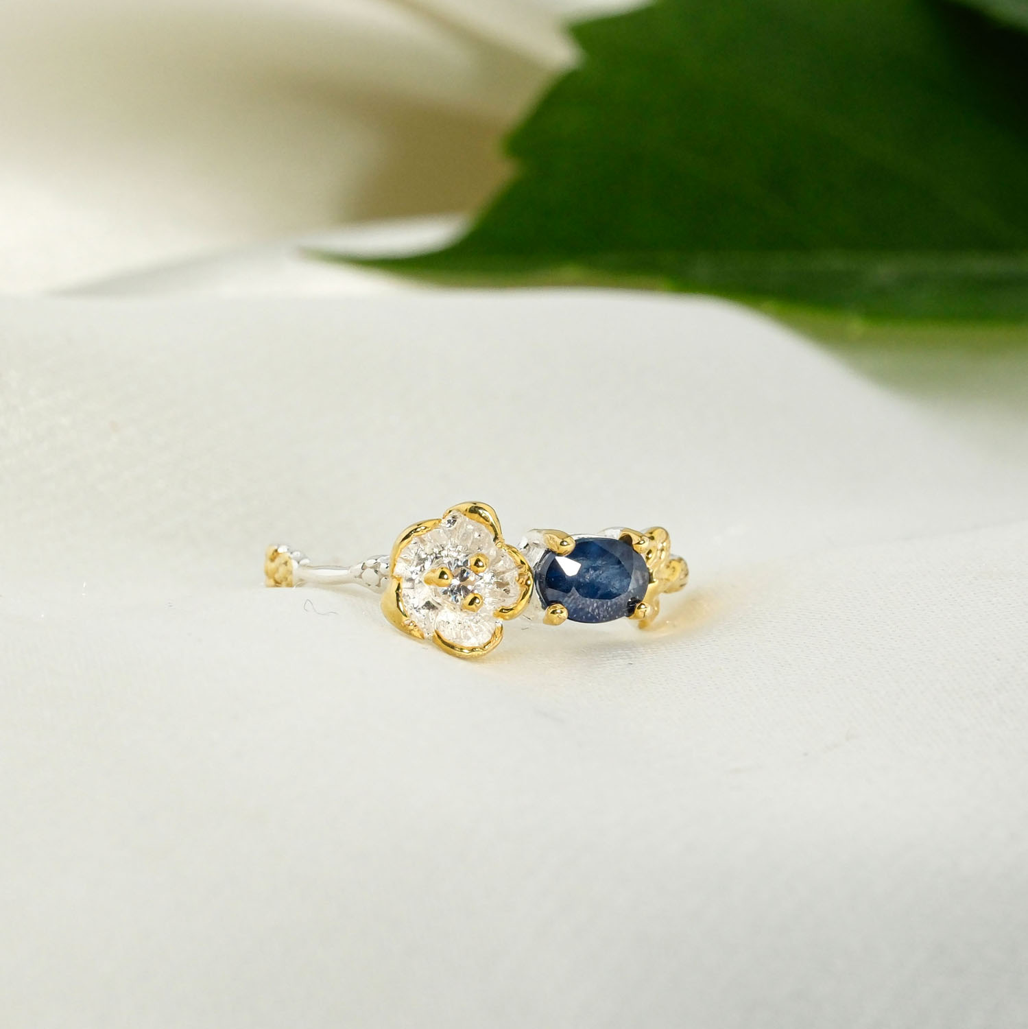 zenski-prsten-prirodni-plavi-safir-cvijet-srebro-925 Orijinal yatay oval mavi safir taşlı gold detaylı gümüş çiçek figürlü ve dal dokulu 925 ayar gümüş kadın yüzük.