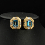 Boucles d'oreilles clous en argent 925 plaqué or avec topazes bleues naturelles taille émeraude et halo de zircons.