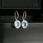 Boucles d'oreilles pendantes pour femme en argent 925 avec topaze bleue naturelle facettée ovale.