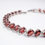 Bracelet de haute joaillerie en argent 925 rhodié avec grenats rouges naturels ovales en ligne tennis.