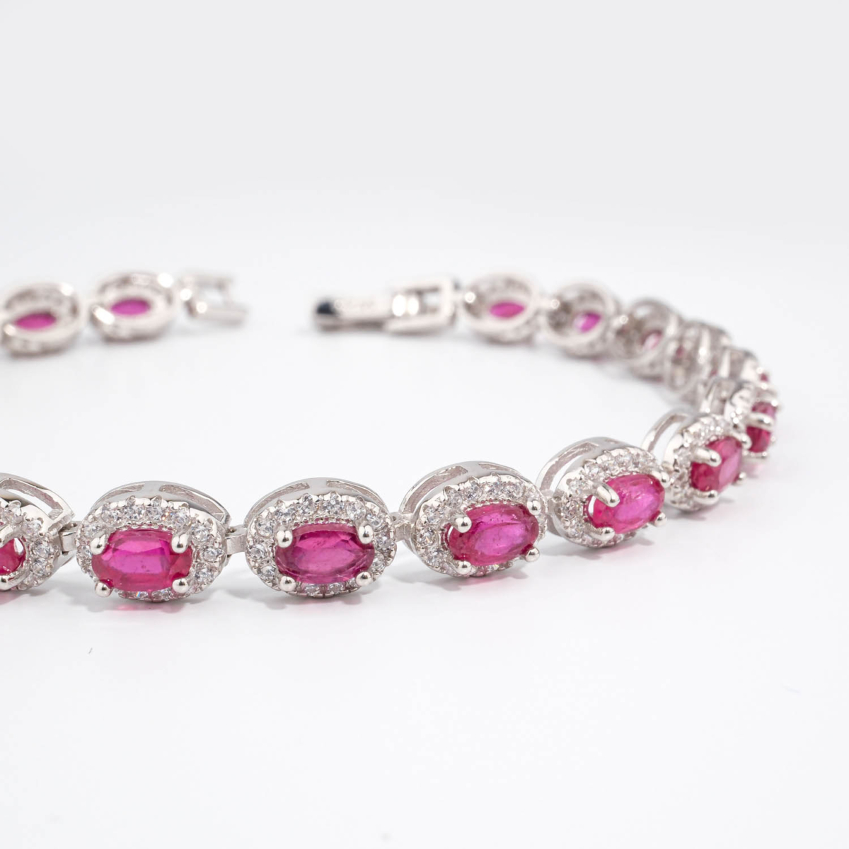 Bracelet de haute joaillerie en argent 925 rhodié avec rubis naturels ovales et halo de zircons étincelants.