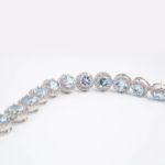 Bracelet de haute joaillerie en argent 925 rhodié avec topazes bleues naturelles rondes et halo de zircons étincelants.