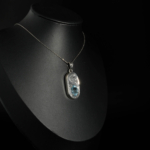 An authentic natural faceted oval light blue aquamarine gemstone hand engraved 925 sterling silver unisex pendant.