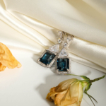 An authentic natural 12ct emerald-cut London blue topaz gemstone 925 sterling silver trilliant halo dangle earrings.