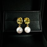 A luxurious pair of gold-plated 925 silver stud dangle earrings featuring oval peridot gems and natural ocean pearls.