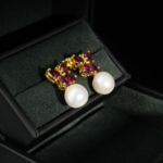 A luxurious pair of gold-plated 925 silver stud dangle earrings featuring pink tourmaline butterflies and ocean pearls.