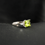 An authentic natural princess-cut green peridot gemstone 925 sterling silver ring with baguette side stones.