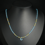 A handcrafted 925 silver women's necklace with faceted blue topaz teardrop pendant, peridot, and gold hematite beads.