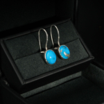 A luxurious pair of 925 sterling silver dangle earrings featuring natural blue turquoise gemstones with pyrite veins.