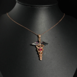 Pendentif médical en argent 925 plaqué or rose représentant le caducée d'Hermès avec rubis naturel et ailes noires.