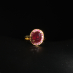 Bague de prestige en argent 925 plaqué or ornée d'un rubis rouge naturel ovale facetté entouré d'un halo rose sur fond noir.