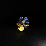 Bague florale d'exception en argent 925 plaqué or ornée de saphirs bleus naturels, saphir jaune et rubis sur fond noir.
