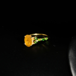 Bague florale d'exception en argent 925 plaqué or ornée d'un saphir jaune naturel facetté et de grenats tsavorites sur fond blanc.