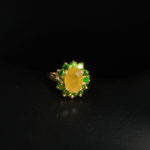 Bague florale d'exception en argent 925 plaqué or ornée d'un saphir jaune naturel facetté et de grenats tsavorites sur fond blanc.