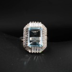 Bague cocktail pour femme en argent 925 ornée d'une topaze bleue naturelle taille émeraude avec halo.